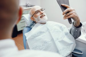 a man is at the dentist and enjoying his smile after gum disease thanks to periodontal treatments